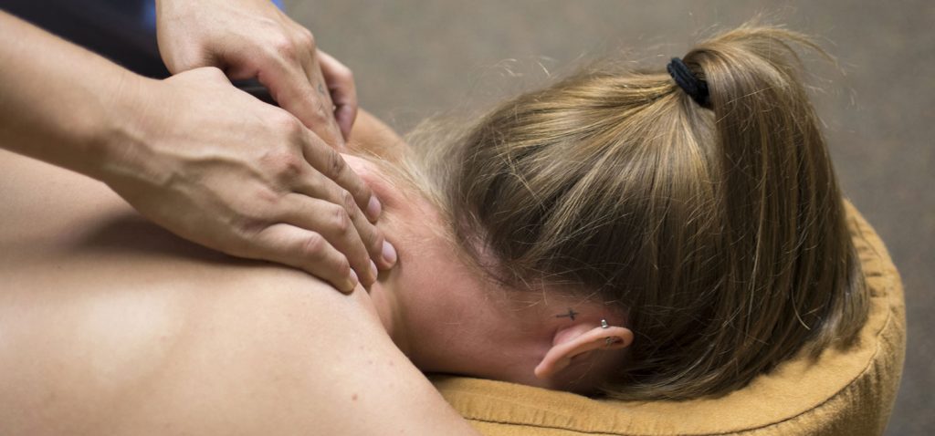 Nacken-Massage Frau in Nahaufnahme, auf Massagebett am Bauch liegend, erhält Nacken-Massage.