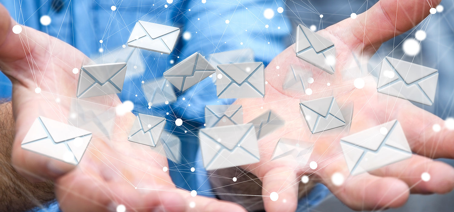 Symbolbild: Blauer Hintergrund, geöffnete Hände in Nahaufnahme werfen viele kleine E-Mail-Kuvert-Symbole in die Luft - sdecoret/Shutterstock.com