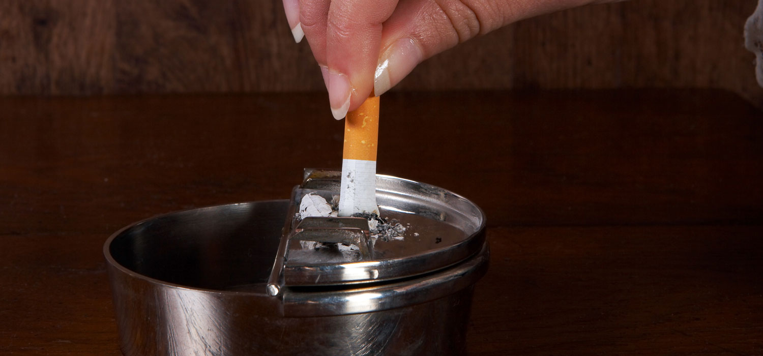 Männerhand, die in einem Aschbecher akurat eine Zigarette ausdämpft. - Anneka/Shutterstock.com